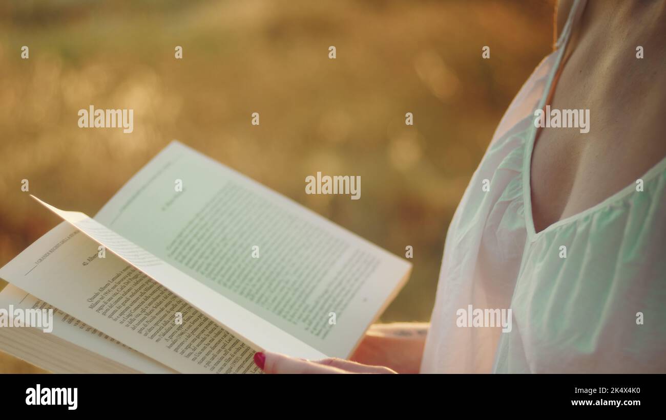 La donna si rilassa leggendo un libro al tramonto Foto Stock