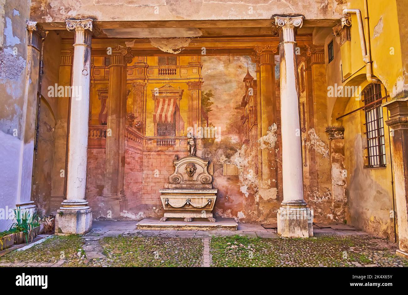 Il cortile di palazzo storico con affreschi medievali conservati e fontana scolpita, decorato con angelo, Brescia, Lombardia, Italia Foto Stock