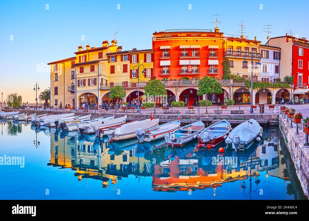 Vista panoramica di Porto Vecchio (Porto Vecchio) con barche ormeggiate e belle case storiche al tramonto, Desenzano del Garda, Italia Foto Stock