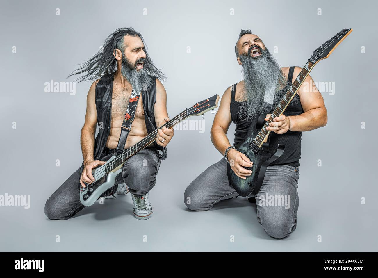 rocker che suonano chitarra e basso, capelli lunghi e barba Foto Stock
