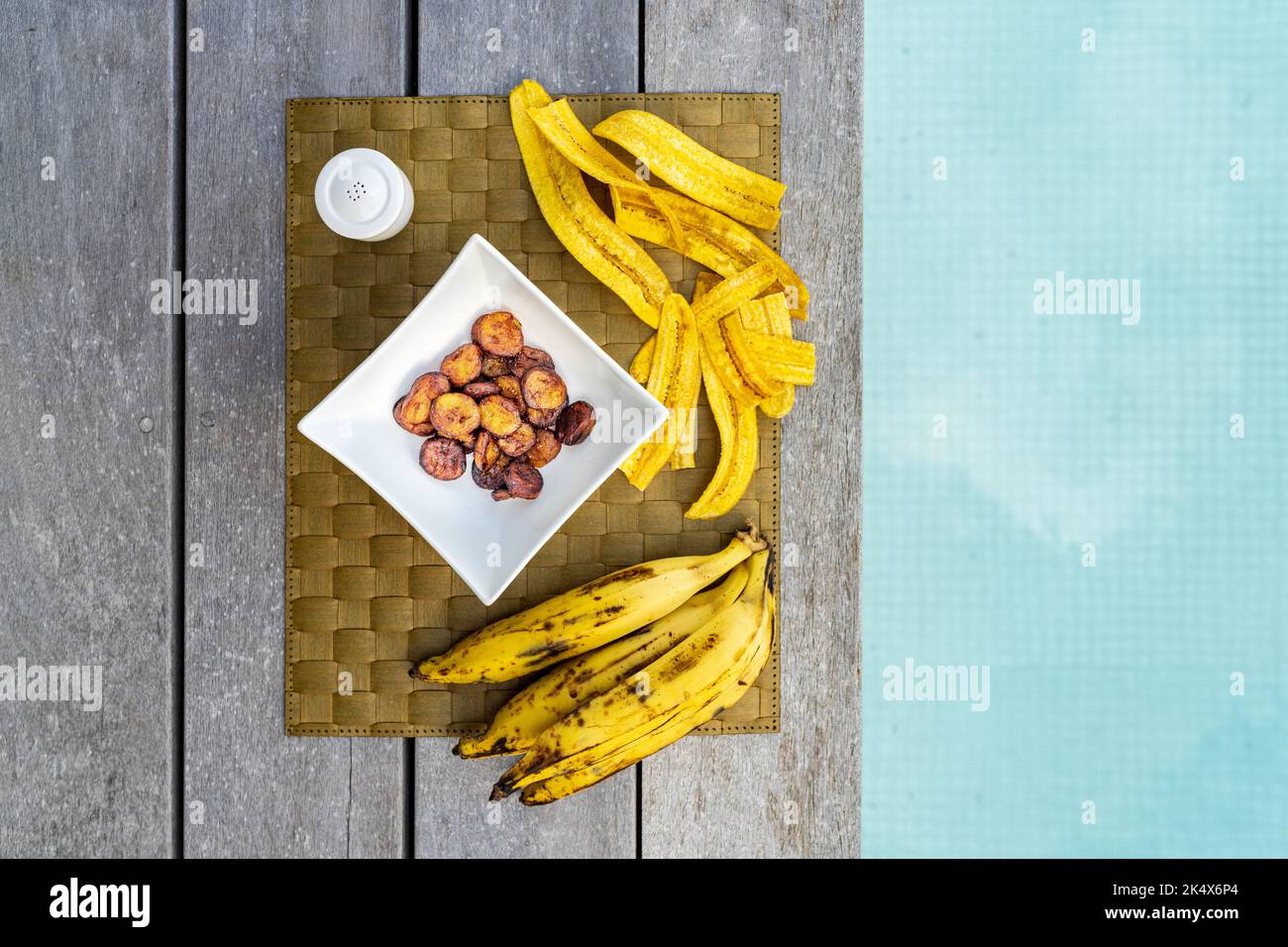 Snack esotico di platano fritto e banane sul placemat sul bordo della piscina, Antigua, Caraibi Foto Stock