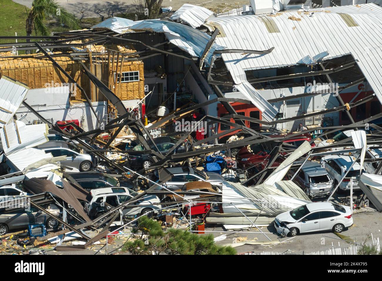 L'uragano Ian distrusse l'edificio industriale con auto danneggiate in rovina in Florida. Disastro naturale e le sue conseguenze. Foto Stock