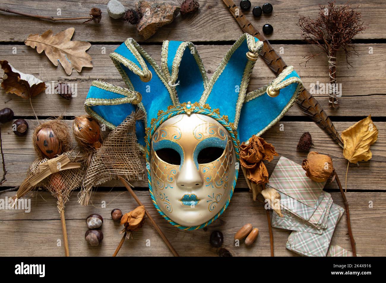 La maschera veneziana si trova su un tavolo di legno con carte di piume e bambole voodoo e oggetti sciamanici, mistero e misticismo Foto Stock