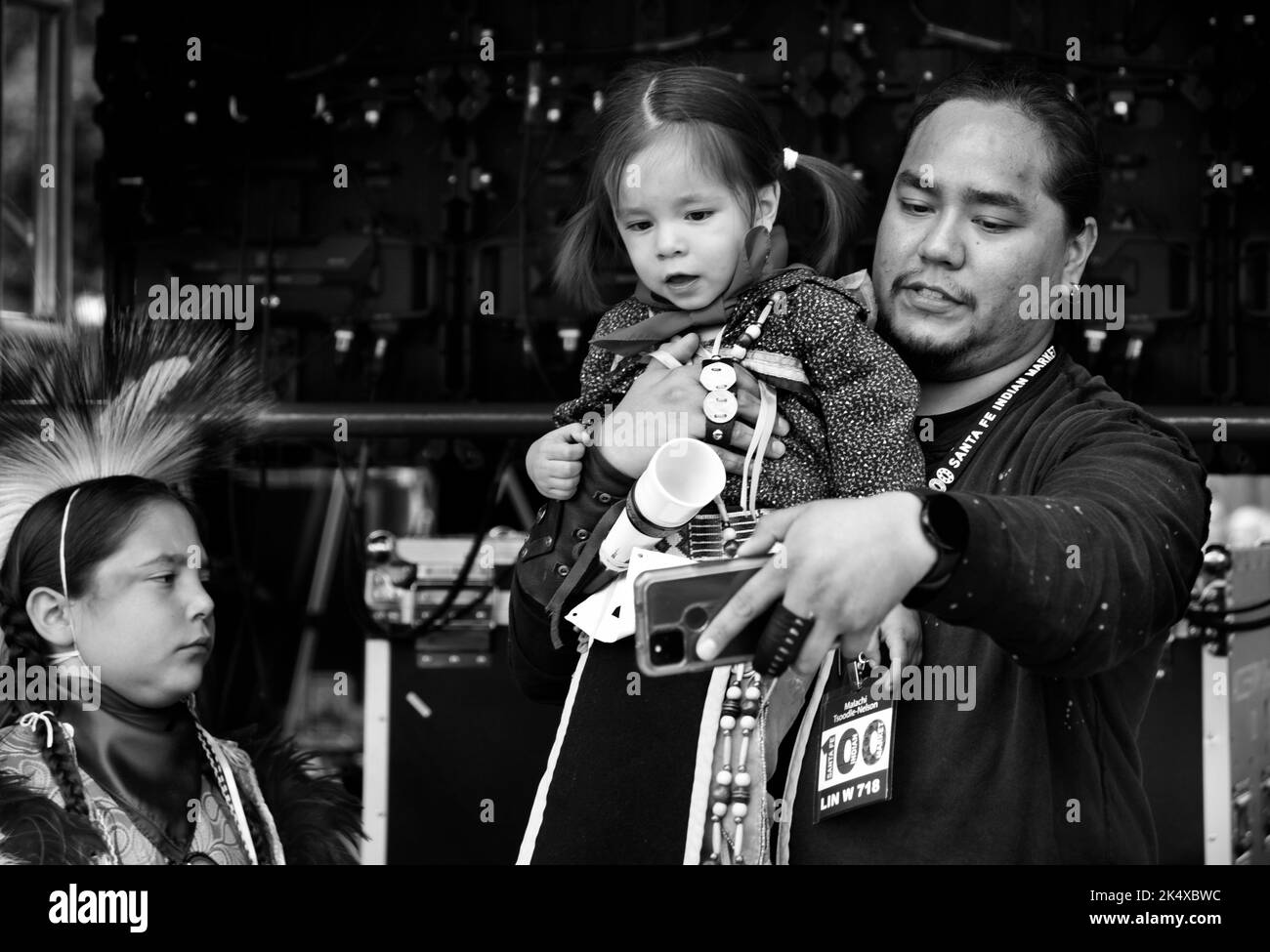 Un uomo nativo americano tiene la sua figlia giovane prima che compete nel concorso di abbigliamento nativo americano al mercato indiano di Santa Fe nel New Mexico. Foto Stock