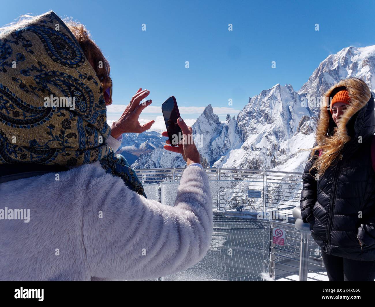 Due donne scattano una foto che si affaccia sul Monte Bianco dalla cima dello Skyway Monte Bianco, un sistema di funivia vicino Courmayeur. Valle d'Aosta, Italia Foto Stock