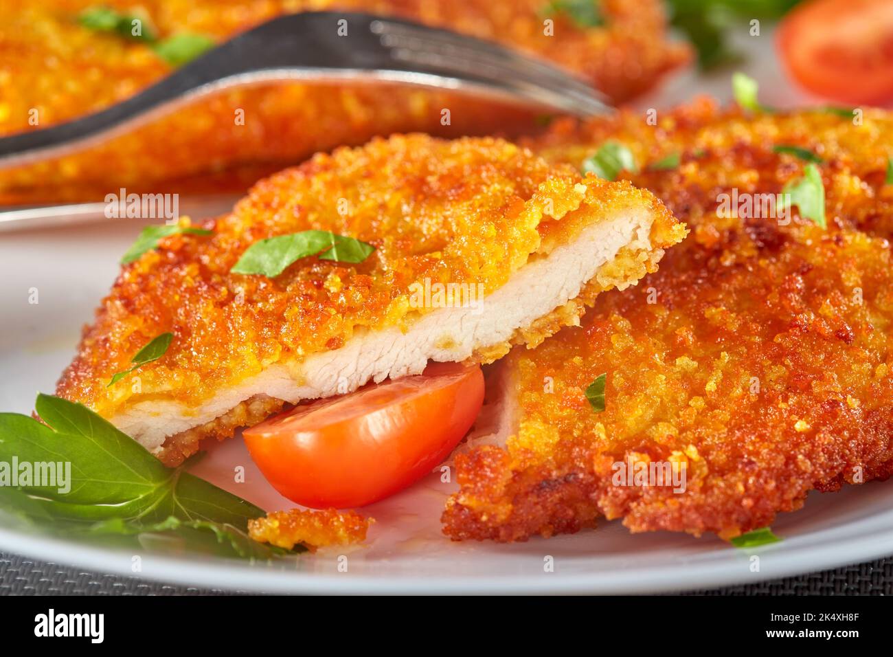 Schnitzel di pollo impanato fresco con pomodori ciliegini ed erbe aromatiche - vista ravvicinata Foto Stock