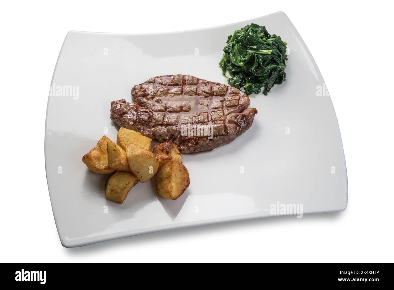 Filetto di manzo alla griglia con spinaci e patate al forno su piatto bianco isolato su bianco Foto Stock
