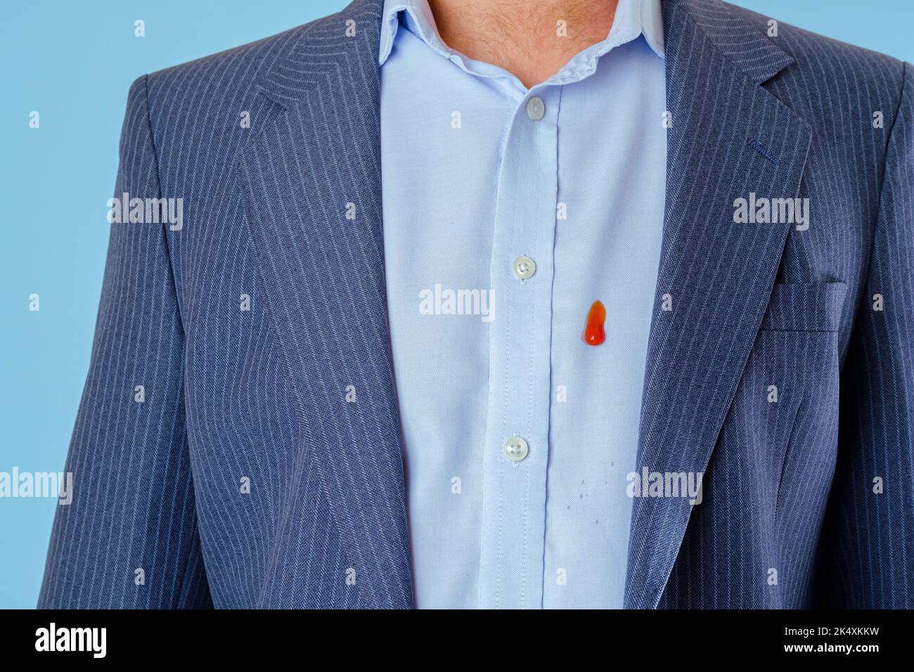 Salsa macchia sulla camicia dell'uomo su sfondo blu. Isolato. Vita quotidiana sporco macchia concetto Foto Stock