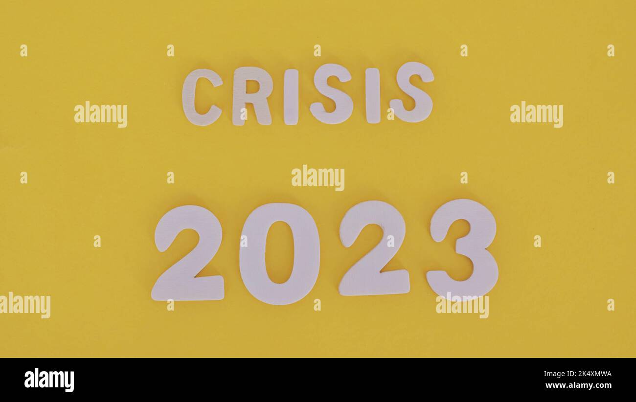 Il concetto di gestione anti-crisi nel nuovo anno 2023. numeri e lettere in legno su sfondo giallo. Crisi economica e il concetto di Foto Stock
