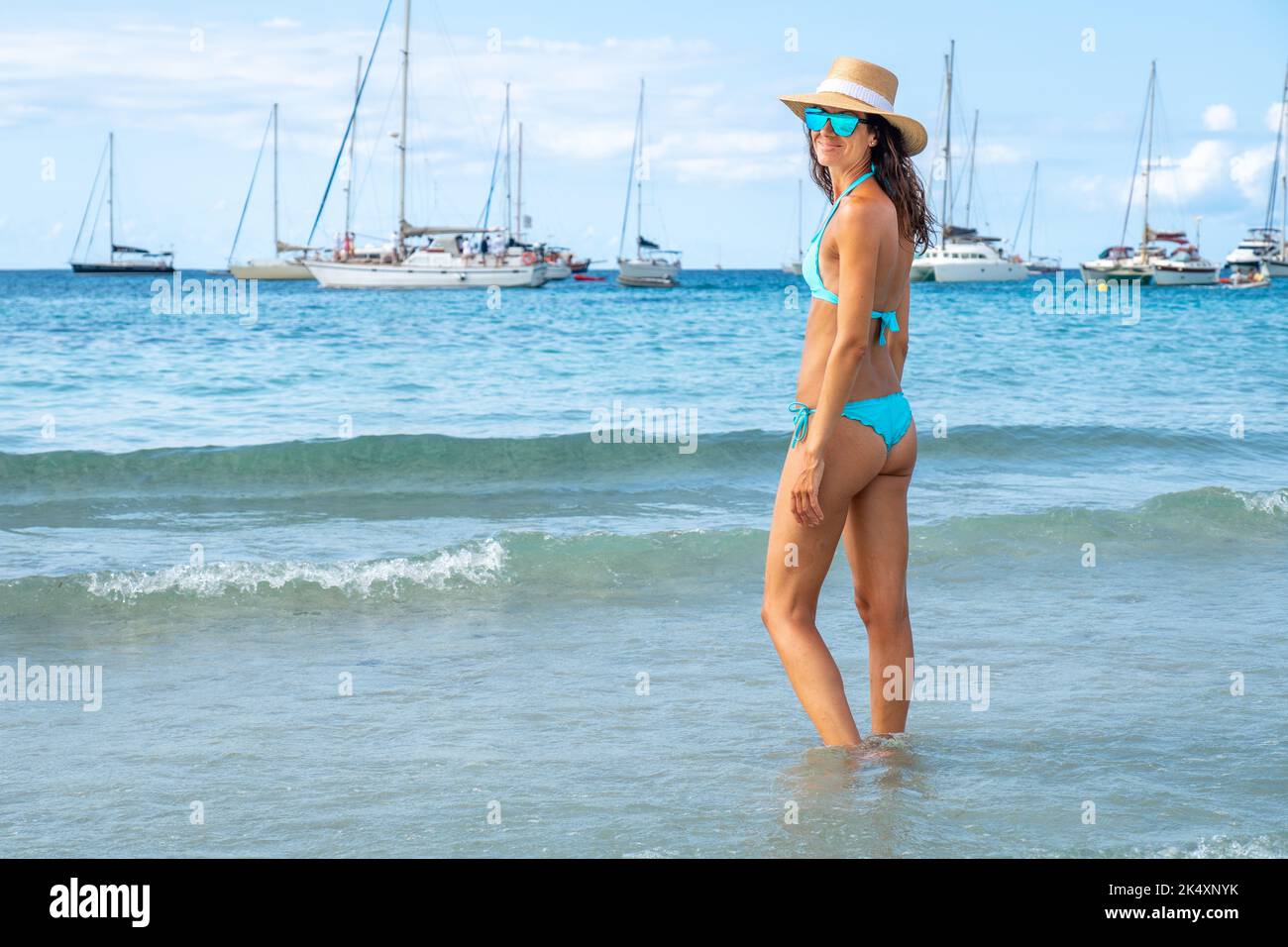 Donna con bikini turchese e cappello in posa su una spiaggia di Ibiza Foto Stock
