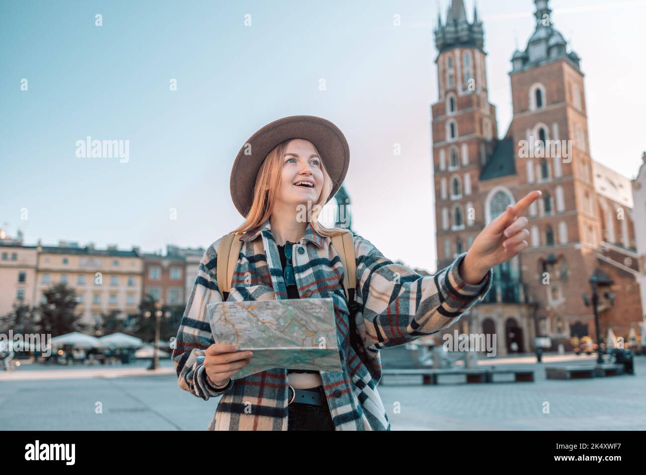 Felice giovane donna con una mappa della città e uno zaino in viaggio nella cresta della città vecchia di Cracovia, Polonia. Concetto di divertimento, viaggio e turismo. Foto Stock