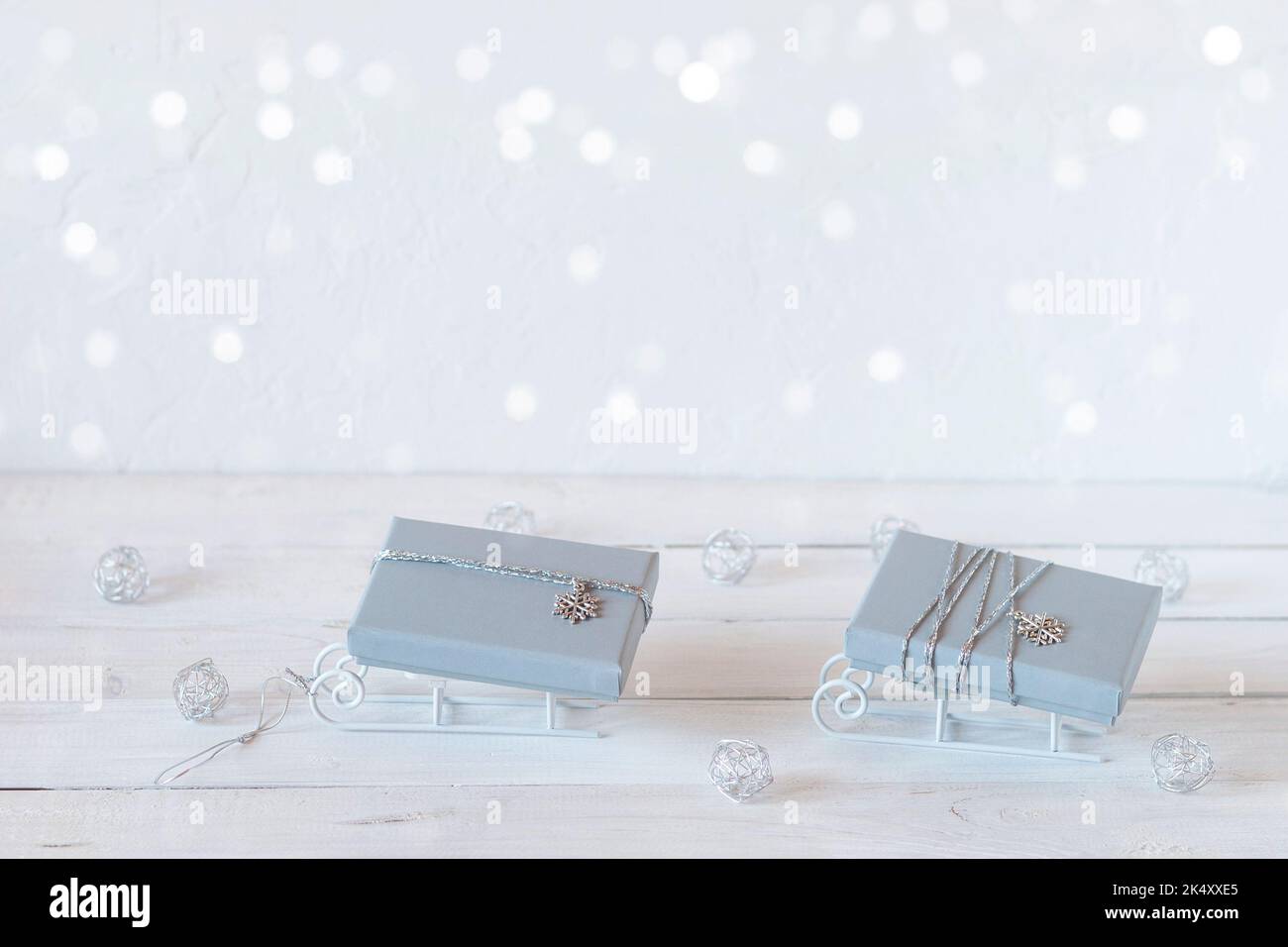 Piccole slitte decorative con scatole regalo di Natale grigie, colori bianco, grigio e argento, spazio copia, idea per il biglietto di Natale Foto Stock