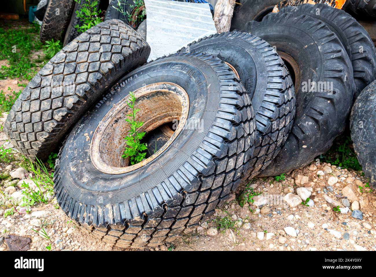 Novgorod, Russia - 26 luglio 2022: Pneumatici vecchi e usati coperti di polvere e ruggine all'aperto. Smaltire gli pneumatici di scarto. Cumulo di pneumatici usati al riciclaggio Foto Stock