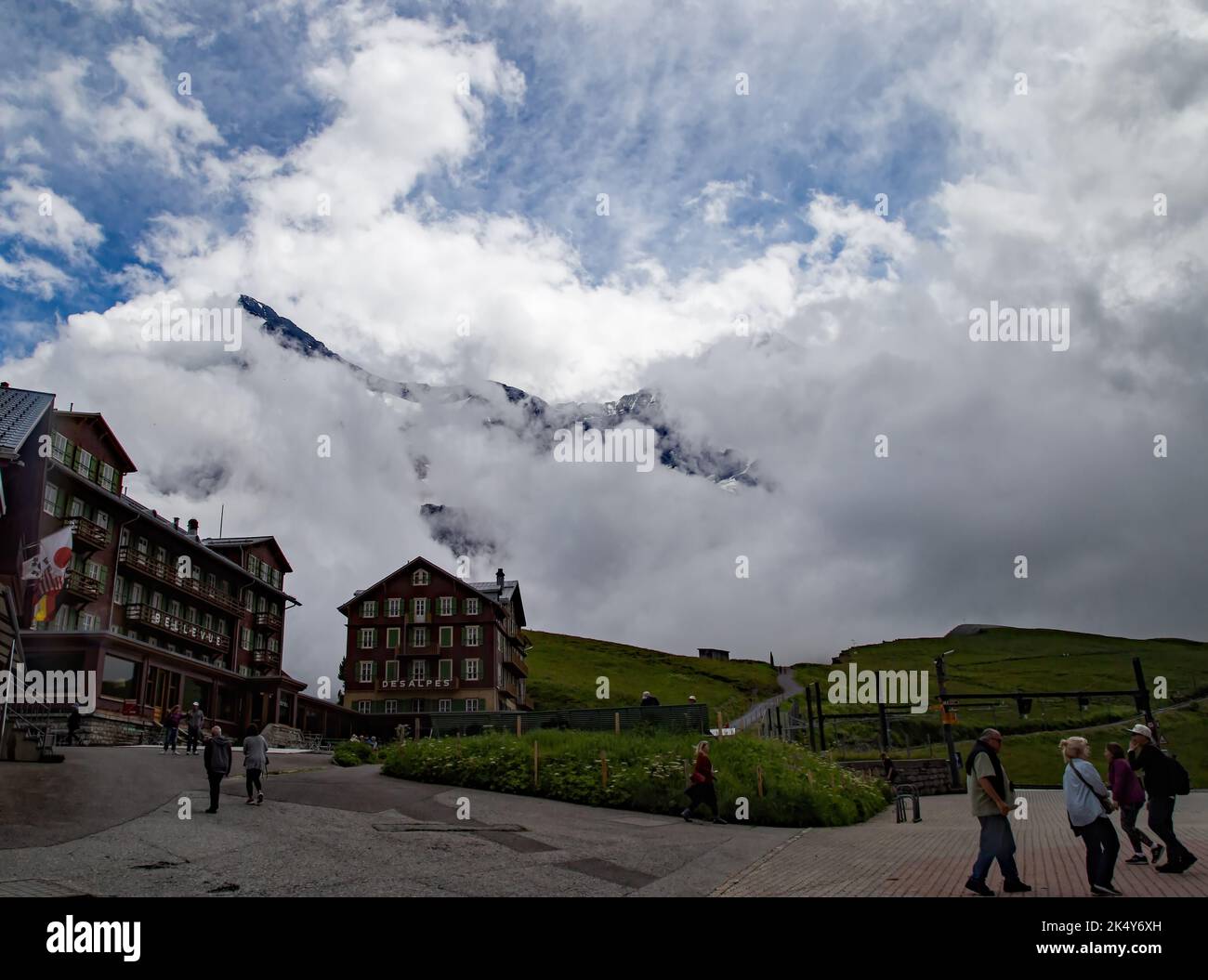 Con Jungfraujoch sullo sfondo tra le nuvole, la città di Kleine Scheidegg è una fermata del treno per i visitatori con un hotel e negozi. Foto Stock