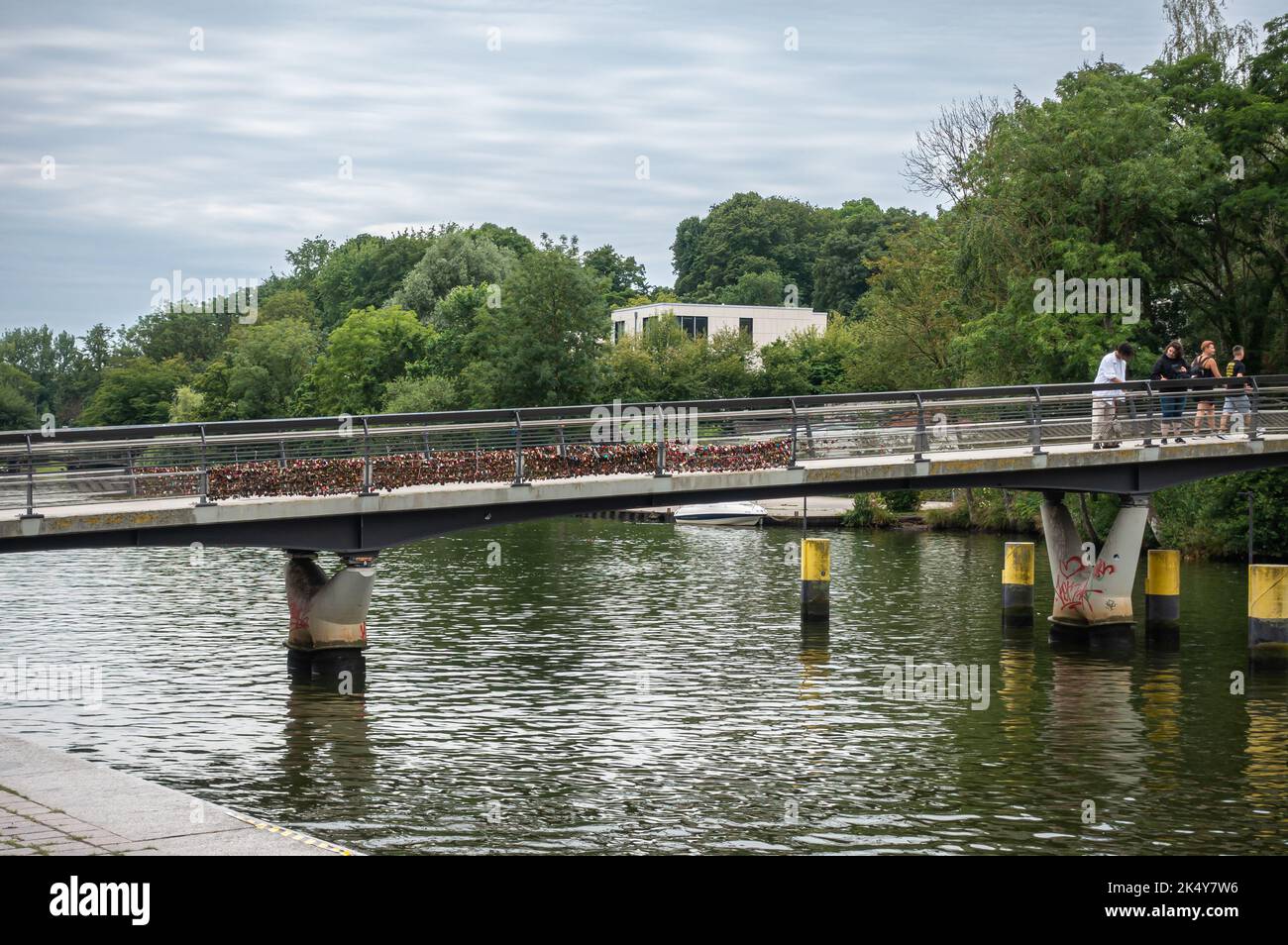 Germania, Lubecca - 13 luglio 2022: Molti Padlock d'amore insieme sulla sezione di Obertravebrucke, ponte sul fiume trave sotto il paesaggio azzurro. Parco verde i Foto Stock