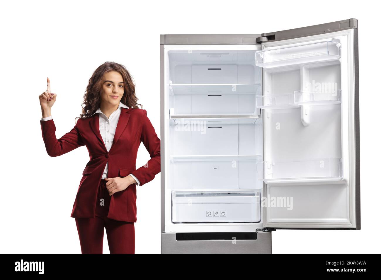 Donna professionista che indica e si appoggia su un frigorifero isolato su sfondo bianco Foto Stock