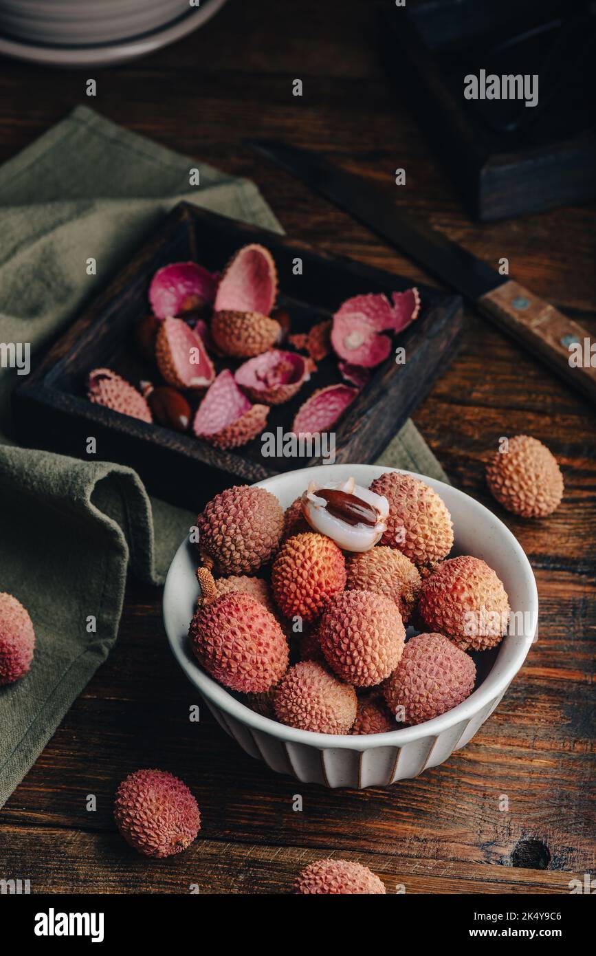 Ciotola vintage di litchi freschi su tavola di legno Foto Stock