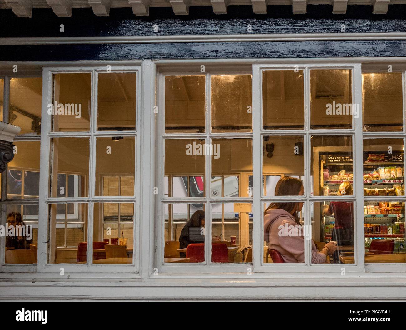 Passeggero femminile in attesa nella sala d'attesa al piano superiore della stazione ferroviaria di York. Foto Stock