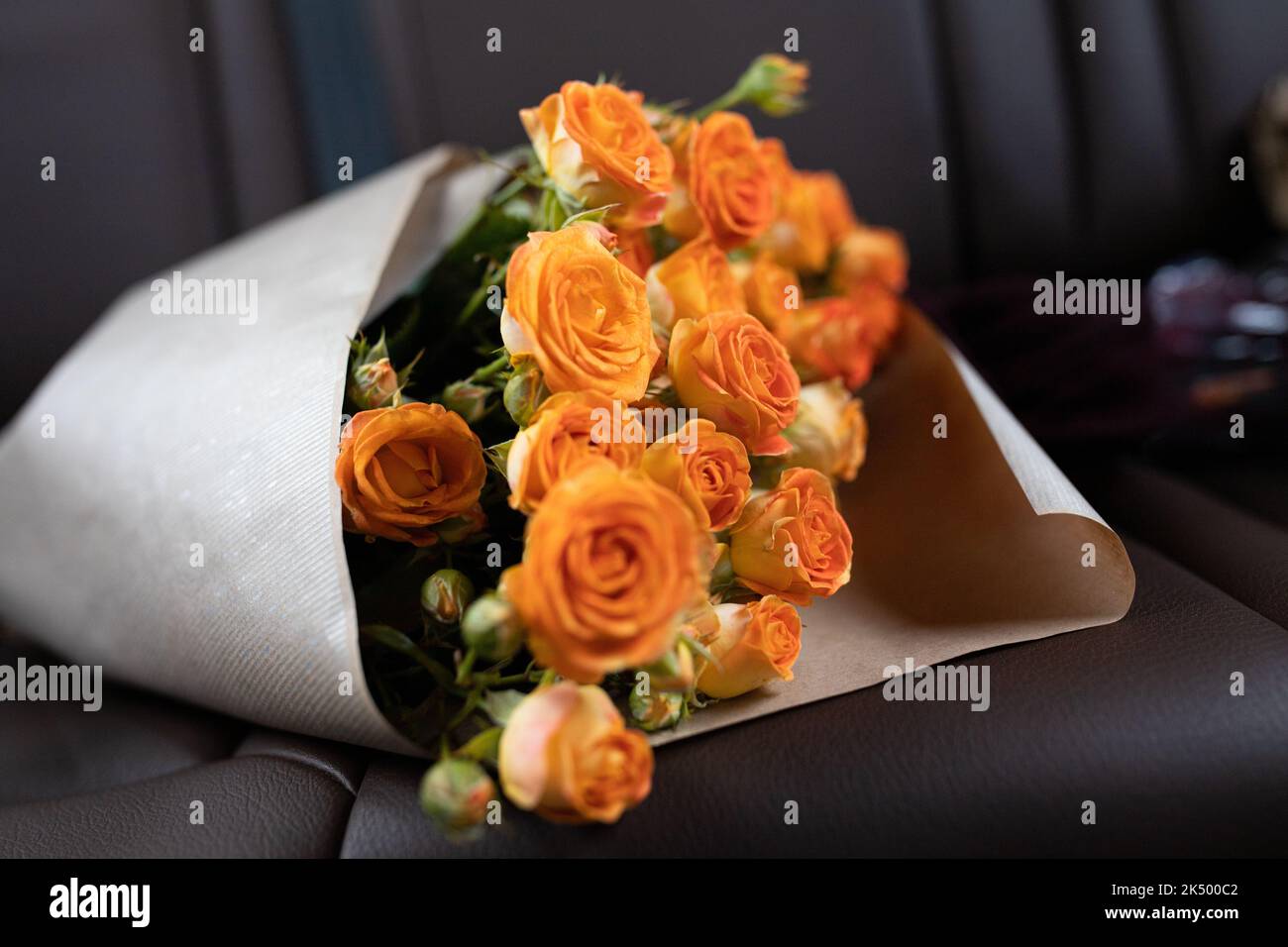 Un bouquet di rose arancioni sul sedile posteriore di un'auto con interni in pelle. Vista frontale. Foto Stock