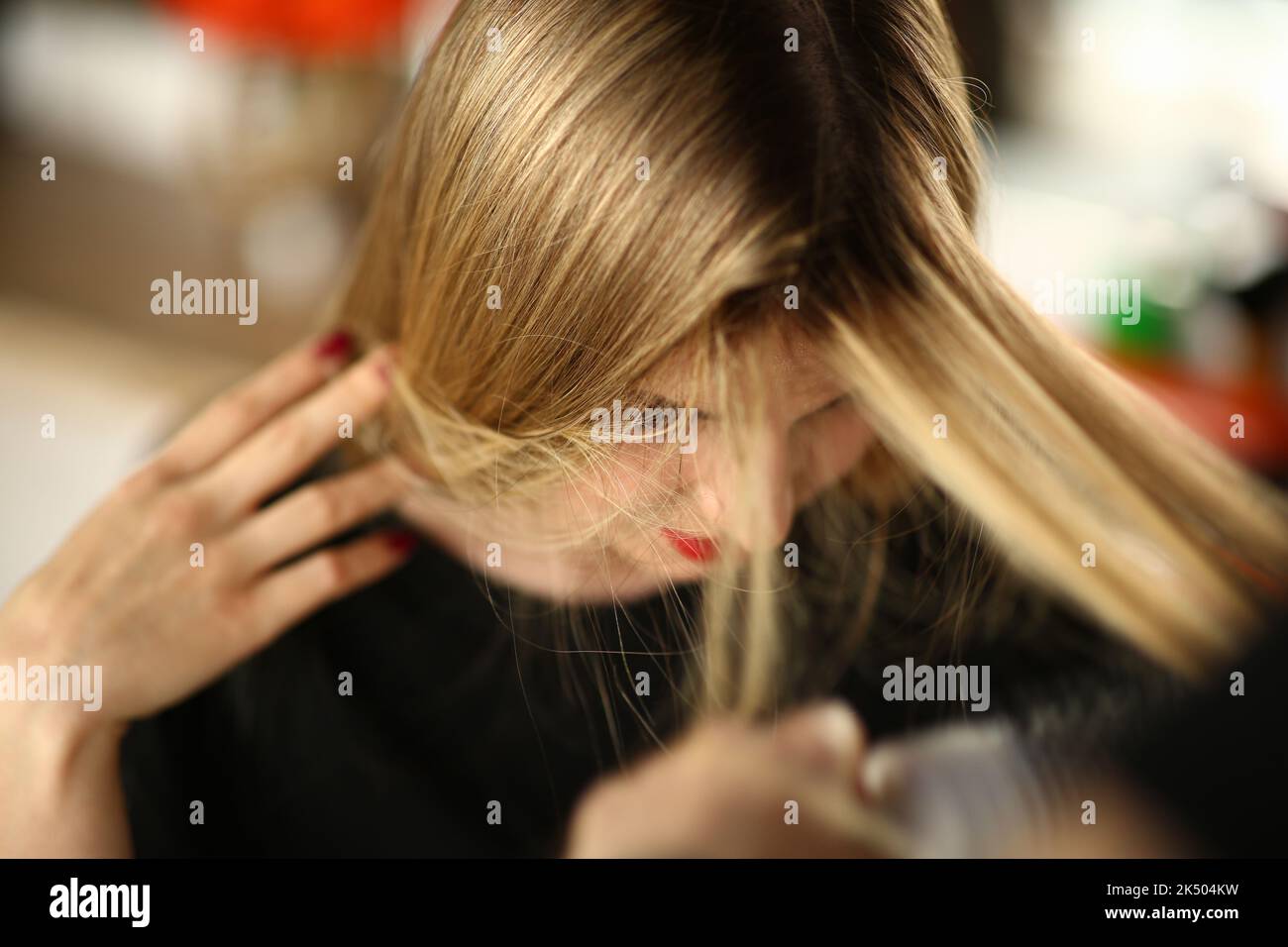 Giovane donna bionda dimostra radici di capelli ricrescita Foto Stock