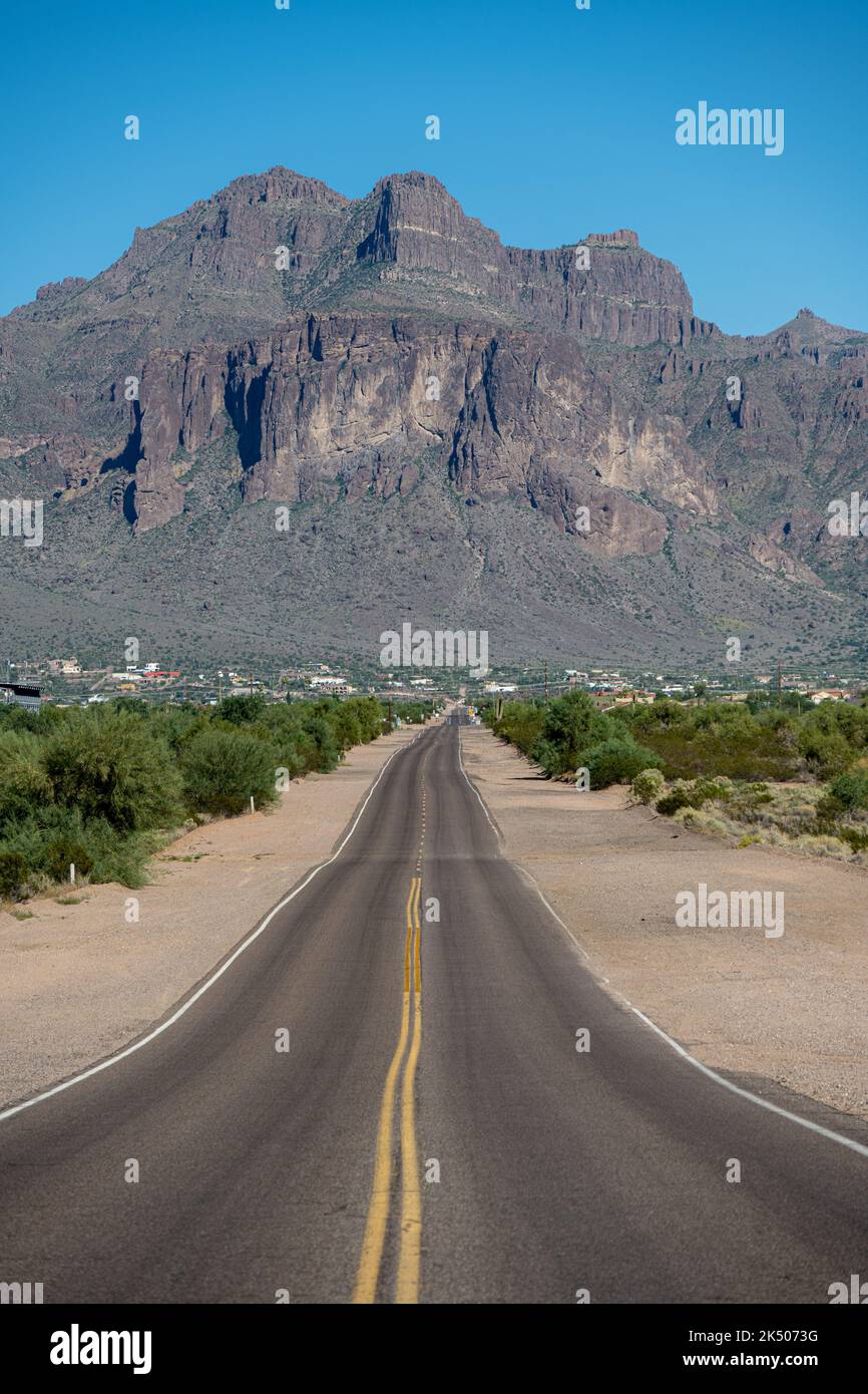 In piedi su una strada diritta che conduce alle Superstition Mountains Foto Stock