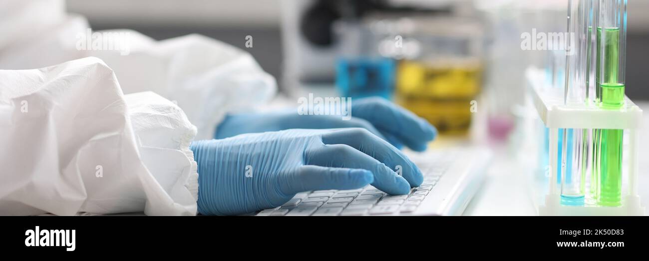 Mani di scienziato in guanti lavora sulla tastiera in laboratorio primo piano Foto Stock