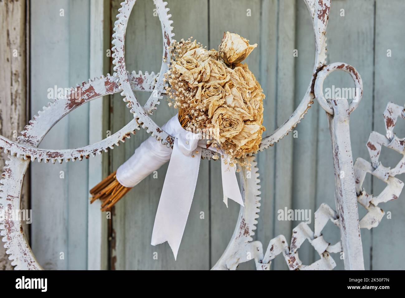 Bouquet di rose secche, legato con nastro bianco, in porta di ingranaggi metallici Foto Stock
