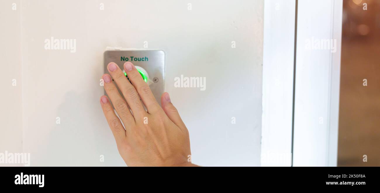 Aprire la porta con la mano tramite l'interruttore No touch Sensor sulla parete dell'ufficio o dell'appartamento. Senza contatto, moderno, tecnologia e concetto di sicurezza Foto Stock
