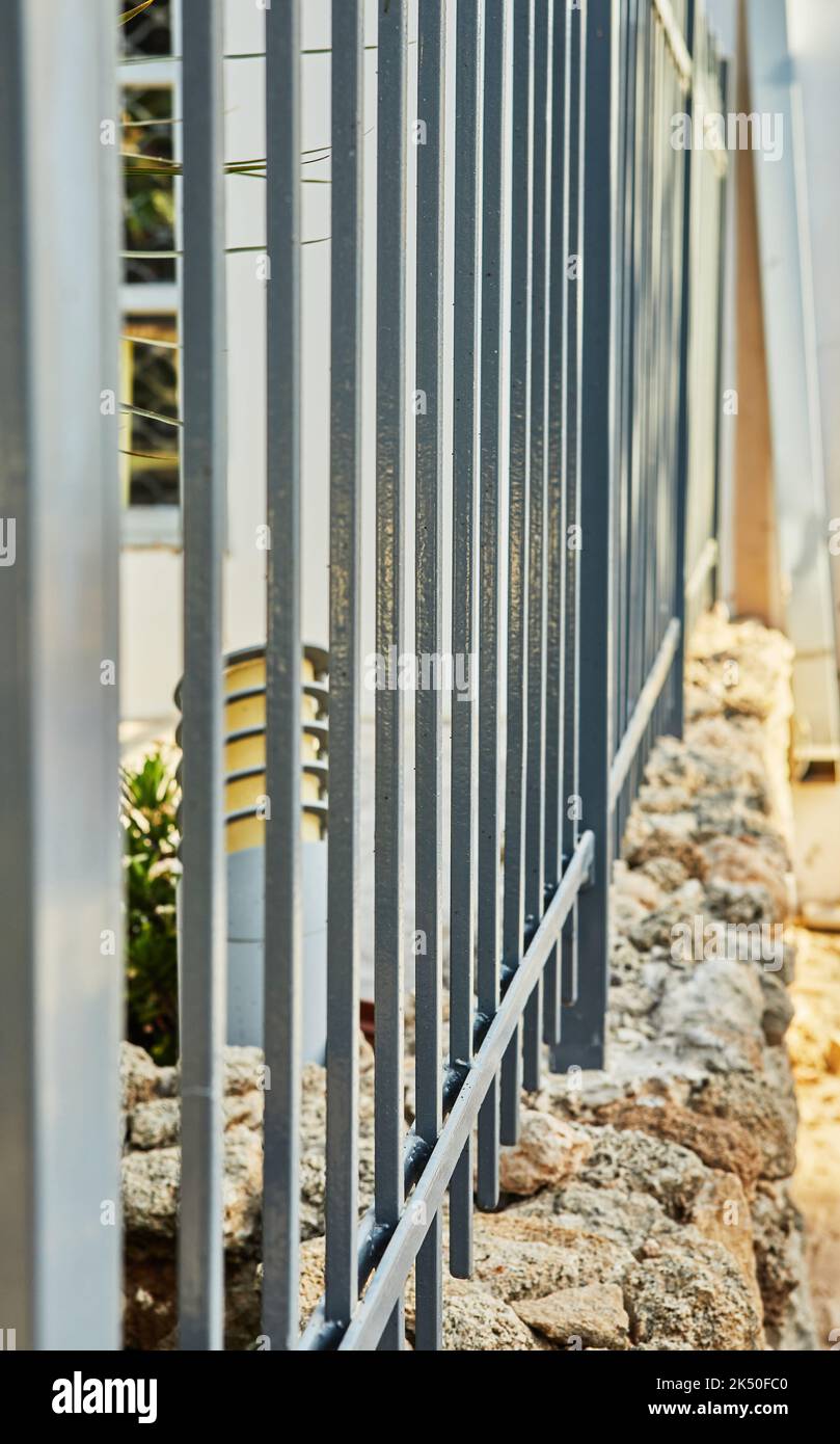 Recinzione di metallo su recinzione di pietra intorno alla casa Foto Stock