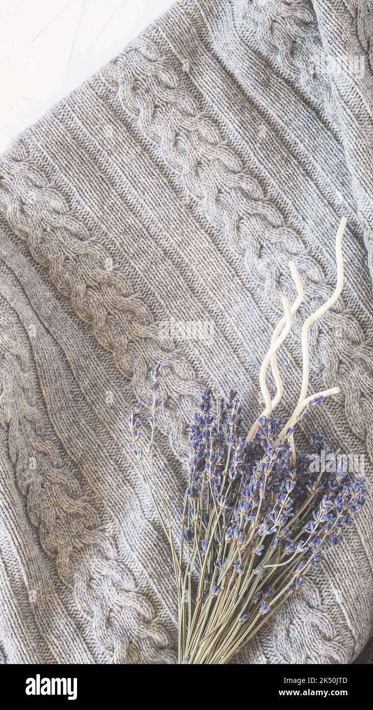 Confortevole coperta grigia lavorata a maglia, un bouquet di lavanda e bastoncini aromatici Foto Stock