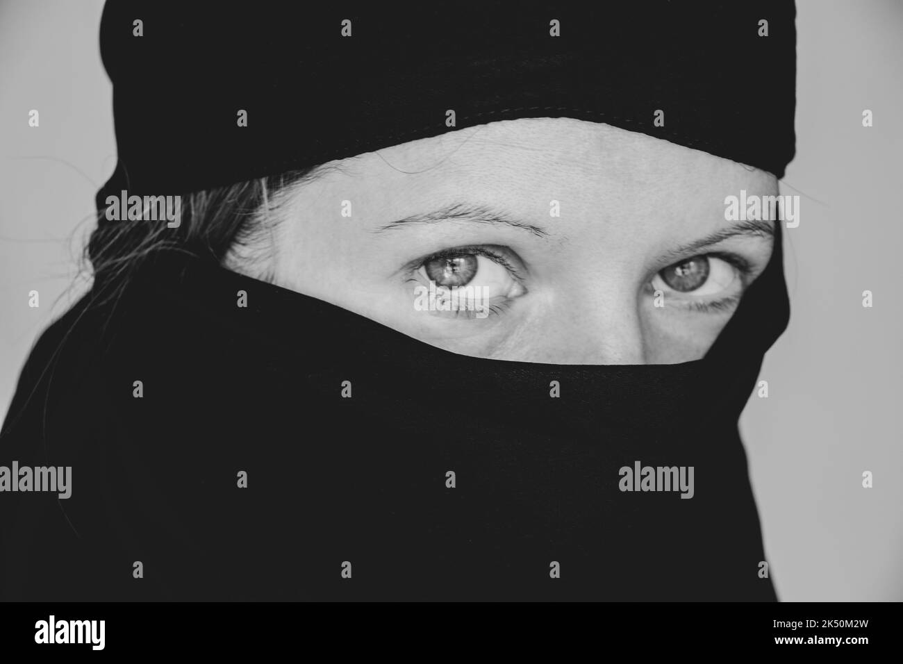La ragazza ha coperto il viso e la testa con una sciarpa nera su uno sfondo isolato, la fede e la religione è musulmana Foto Stock