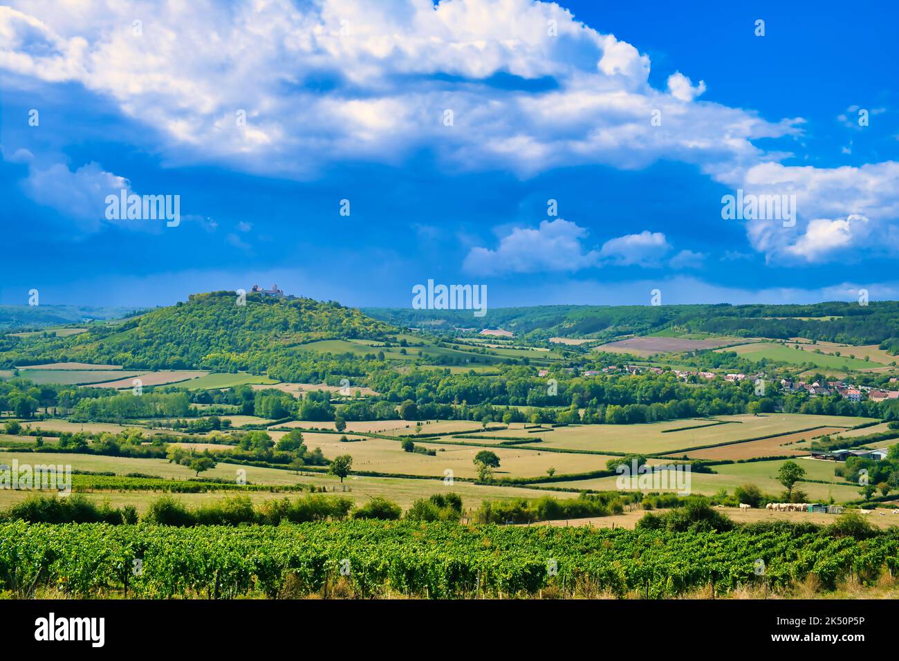 La collina di Vézelay, Morvan, Borgogna, Francia. Circondato da piccoli terreni agricoli, alberi e vigneti. Soleggiato, con nuvole di tuoni che si innalzano Foto Stock