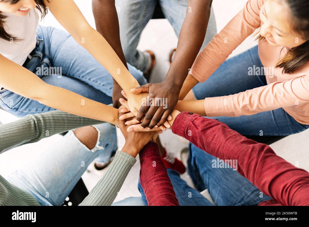 Giovani multietnici che mettono insieme le mani mostrando unità e lavoro di squadra Foto Stock