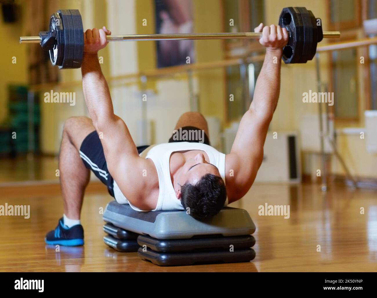 Colpire i pesi. Un giovane uomo muscolare che si allenava in palestra. Foto Stock