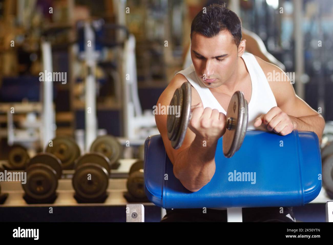 Modellare i suoi bicipiti. Un giovane uomo muscolare che si allenava in palestra. Foto Stock