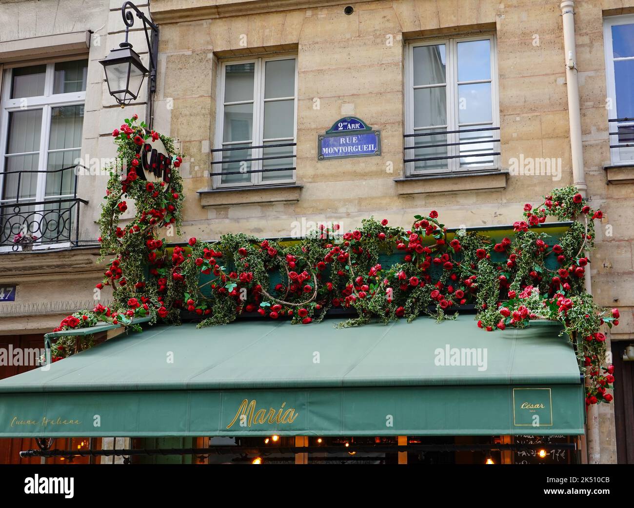 Rose artificiali drappeggiato sopra la tettoia di Cafe Maria, María di César, in rue Montorgueil, 2nd Arrondissement, Parigi, Francia. Foto Stock