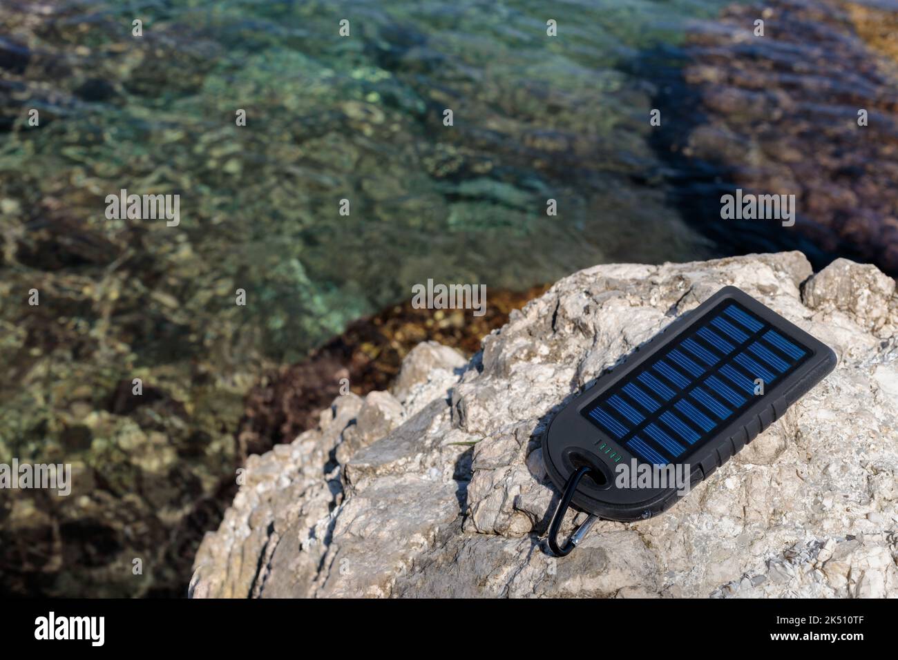Batteria dispositivo di energia solare sullo sfondo di una bella spiaggia. Ricarica dello smartphone dalla batteria solare. Foto Stock