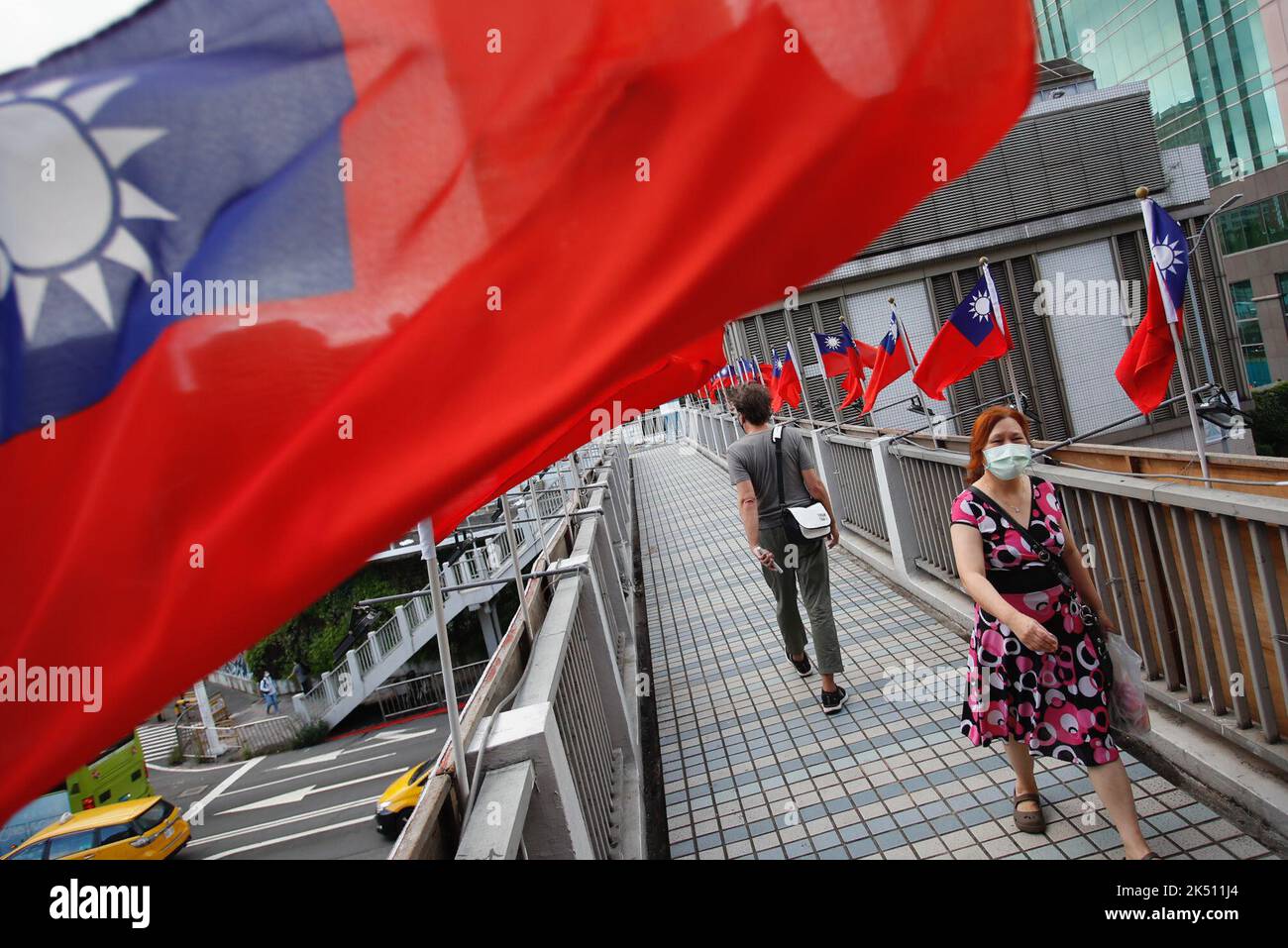 Taipei, Taipei, Taiwan. 5th Ott 2022. I pedoni attraversano una passerella a Taipei, dove le bandiere di Taiwan sventolano davanti alle celebrazioni nazionali dell'isola, tra le crescenti minacce provenienti dalla Cina. L’auto-governante si trova di fronte a bassi tassi di natalità che influiscono sul tasso di ammissione scolastica e sul reclutamento militare, con tensioni crescenti nello stretto di Taiwan mentre Pechino intensifica le esercitazioni militari. Taiwan sta promuovendo relazioni con paesi europei come Germania, Lituania, Estonia e Francia, Stati Uniti, Regno Unito e Canada, Così come i paesi del sud-est asiatico come Singapore e Malesia. (Credit IMA Foto Stock