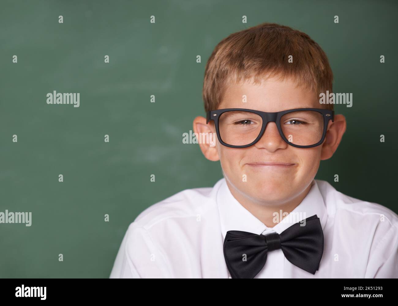 Ragazzo intelligente. Un giovane ragazzo felice con una cravatta che sorride alla telecamera di fronte a una lavagna - copyspace. Foto Stock