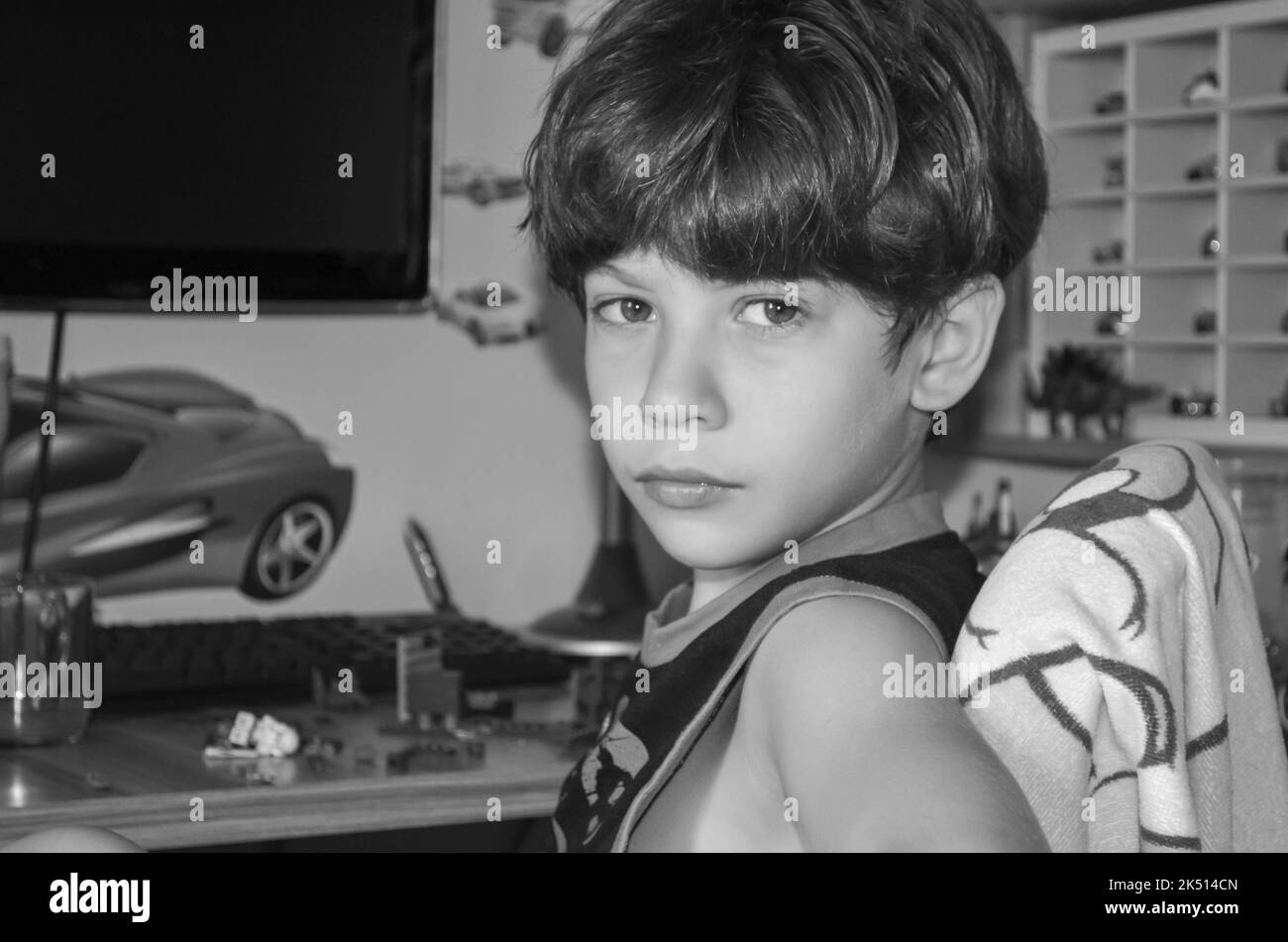 Ritratto in bianco e nero di un bambino tranquillo e serio nella sua camera da letto guardando la fotocamera. Infanzia sana. Salvador, Brasile. Foto Stock