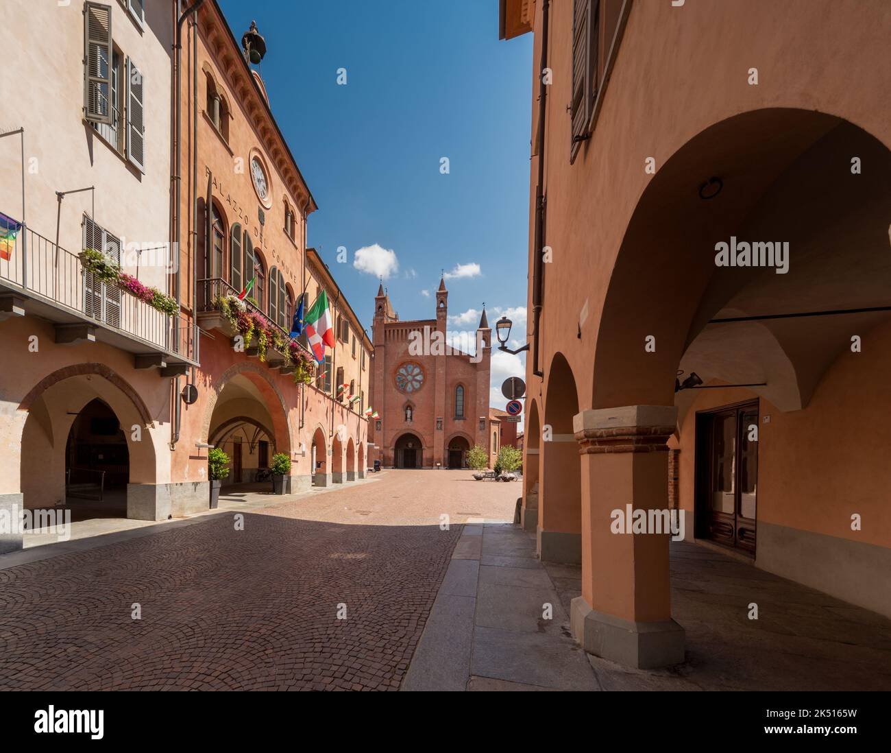 Alba, Langhe, Piemonte, Italia - 16 agosto 2022: Via Cavour con portici medievali e il Municipio con balconi fioriti, sullo sfondo Cathedr Foto Stock