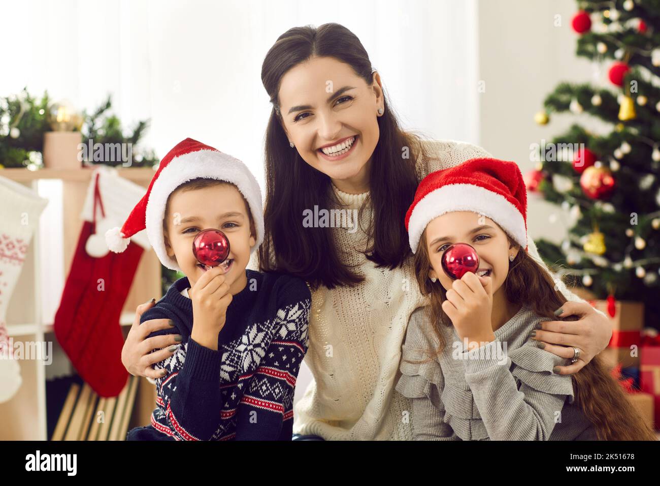 Ritratto di Natale di allegra madre e il suo divertente piccolo figlio e figlia in cappelli di santa. Foto Stock