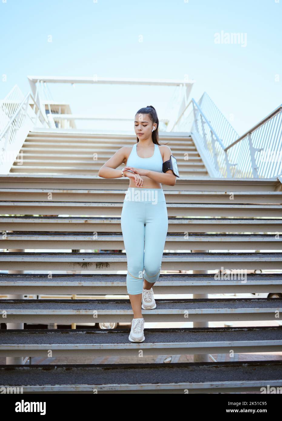 Fitness, smartwatch e monitoraggio della salute con donne sportive che controllano il polso e i progressi durante l'esercizio sulla costruzione di passi in una città. Formazione, tempo e. Foto Stock