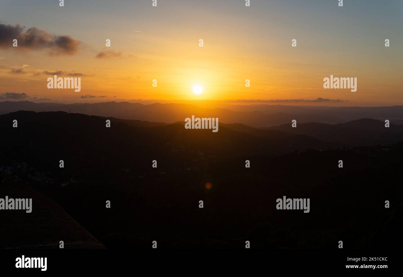 Panorama mozzafiato di sagome di montagne dal parco divertimenti Tibidabo contro il cielo panoramico del tramonto a Barcellona Foto Stock