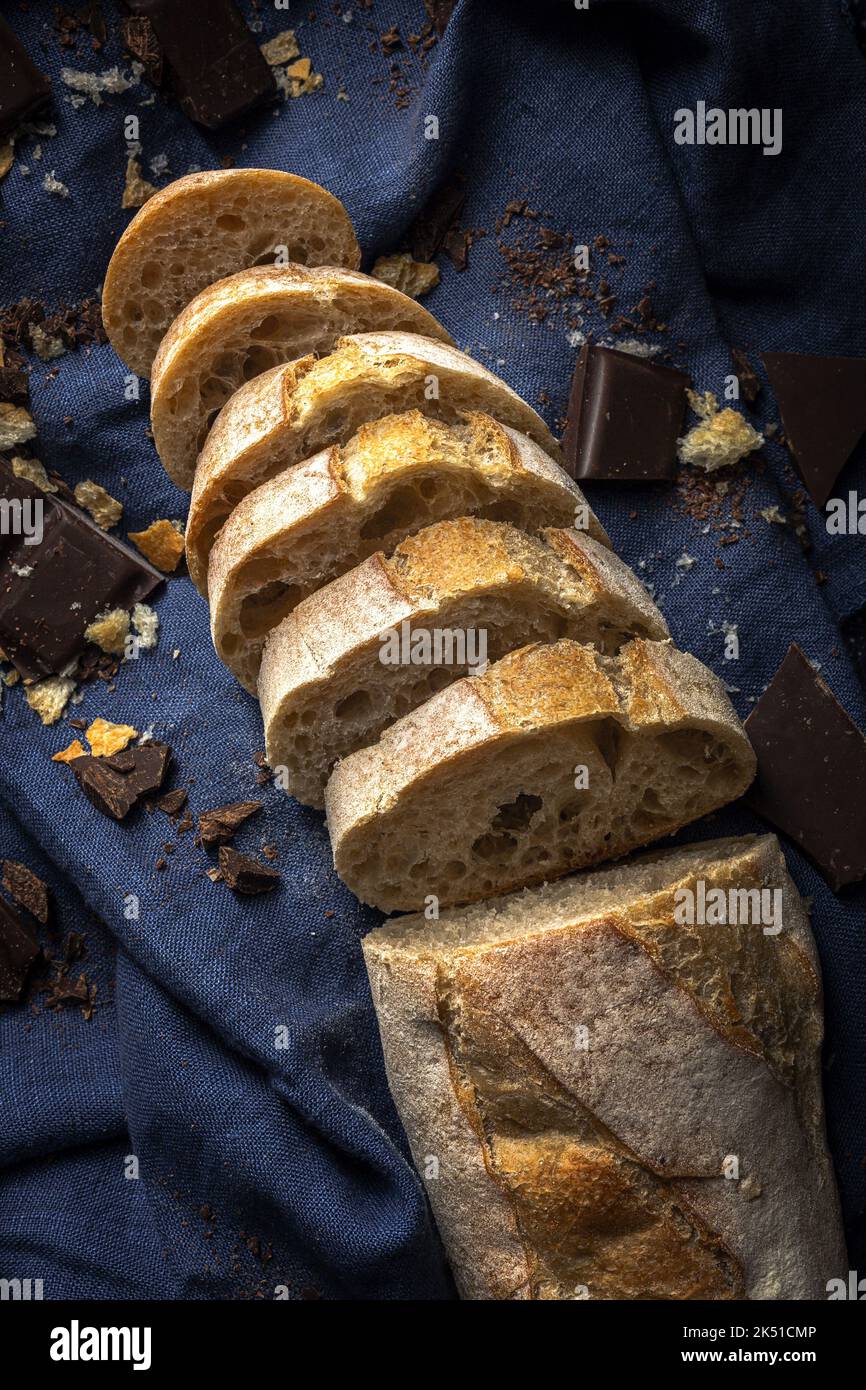 Angolo alto di pane appena sfornato tagliato con barrette di cioccolato poste su tovagliolo blu sul tavolo in cucina Foto Stock