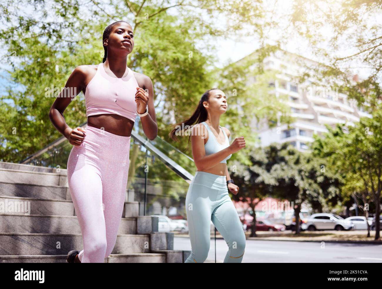 Fitness amici, city running e donne allenarsi insieme per uno stile di vita sano, benessere e maratona di allenamento in città all'aperto. Mettere a fuoco gli atleti Foto Stock