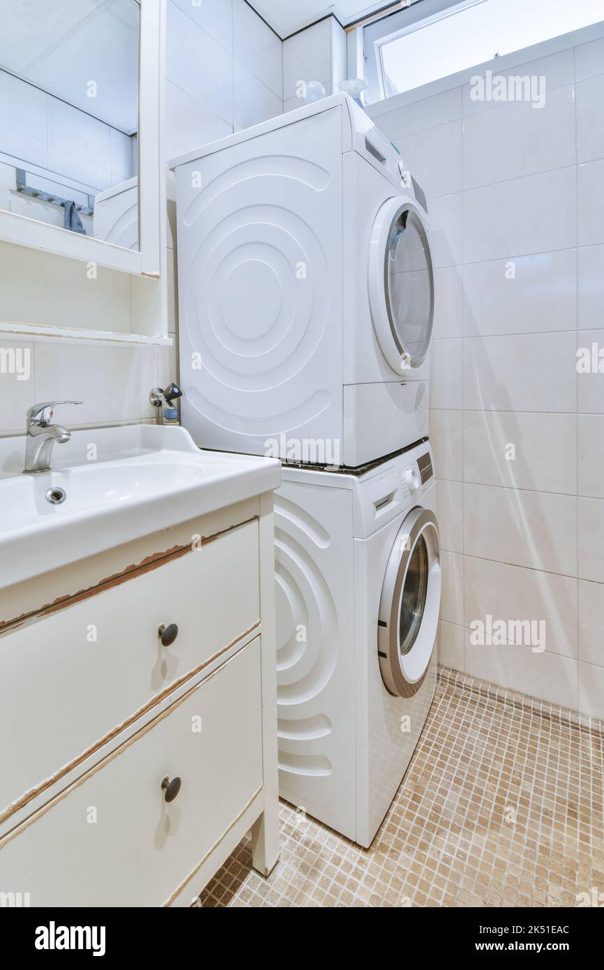 Lavandino con rubinetto e sapone liquido appeso su una parete piastrellata  sotto lo specchio con lavatrice in bagno contemporaneo a casa Foto stock -  Alamy