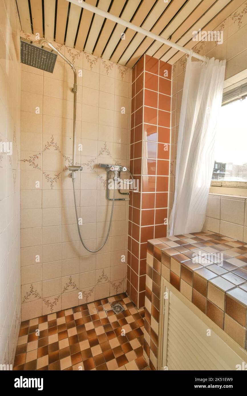 Doccia con rubinetto cromato in antico bagno d'epoca con pareti piastrellate a mosaico Foto Stock