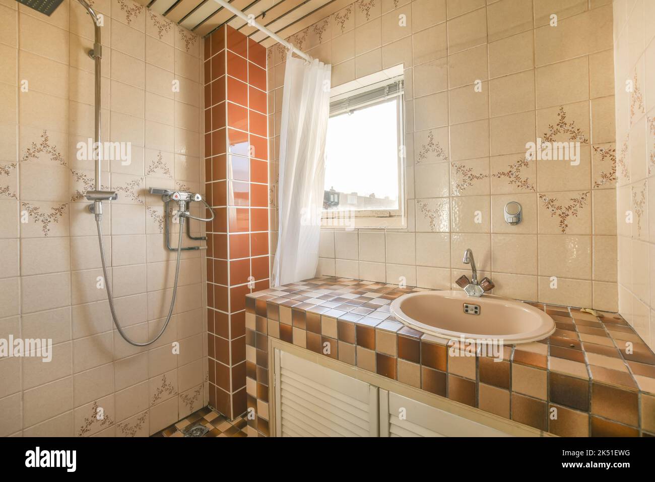 Lavabo in ceramica con rubinetto cromato vicino alla doccia in antico bagno d'epoca con pareti piastrellate in mosaico Foto Stock