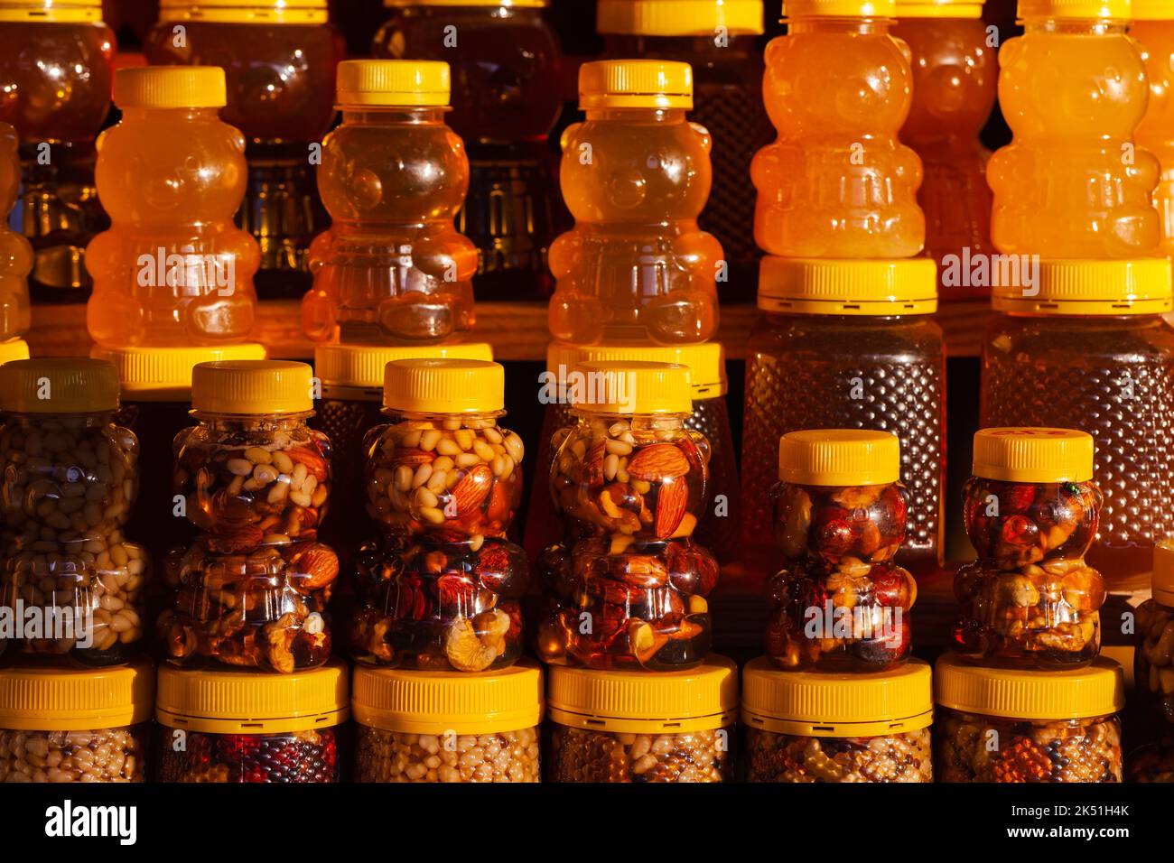 Assortimento di miele con noci in vasetti di plastica a forma di orso stand su una vetrina in una fila. Foto ravvicinata con messa a fuoco morbida selettiva Foto Stock